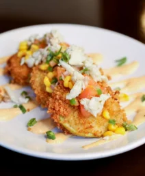 Crispy crab cakes with corn and tomato relish on a plate at a Charlotte boutique hotel.