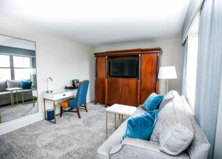 Elegant hotel room with sofa, desk, and TV armoire, inviting family to relax.
