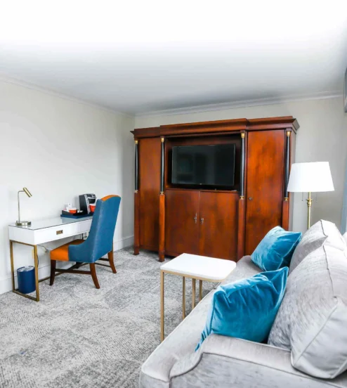 Elegant hotel room with sofa, desk, and TV armoire, inviting family to relax.