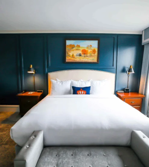 Elegant hotel room at The Dunhill Hotel with a cosy bed and warm decor.