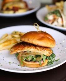 Tasty gourmet chicken sandwich with greens on a plate at The Dunhill Hotel restaurant.