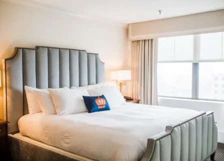 Cosy hotel room with a plush bed, soft lighting, and a large window offering natural light.