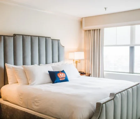 Cosy hotel room with a plush bed, soft lighting, and a large window offering natural light.