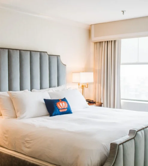 Cosy hotel room with a plush bed, soft lighting, and a large window offering natural light.