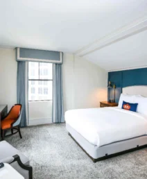 Elegant hotel room with king-sized bed, desk, and modern decor at The Dunhill Hotel.