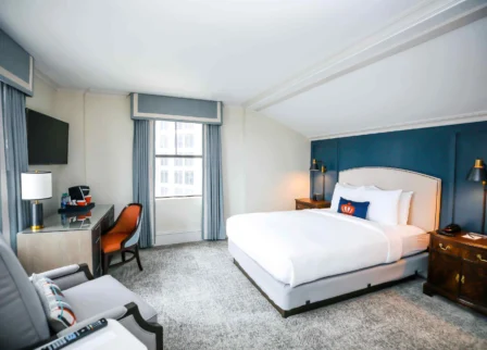 Elegant hotel room with king-sized bed, desk, and modern decor at The Dunhill Hotel.