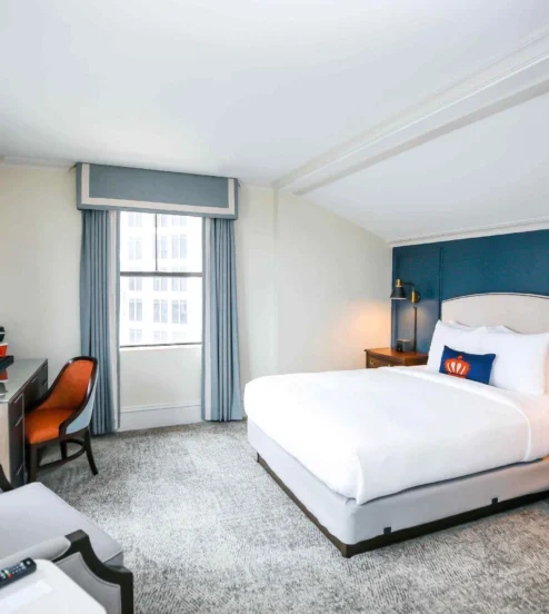 Elegant hotel room with king-sized bed, desk, and modern decor at The Dunhill Hotel.