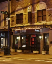 Warmly lit facade of The Dunhill Hotel on a quiet Charlotte street at night.