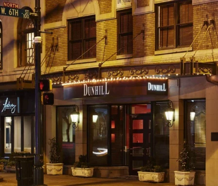 Warmly lit facade of The Dunhill Hotel on a quiet Charlotte street at night.