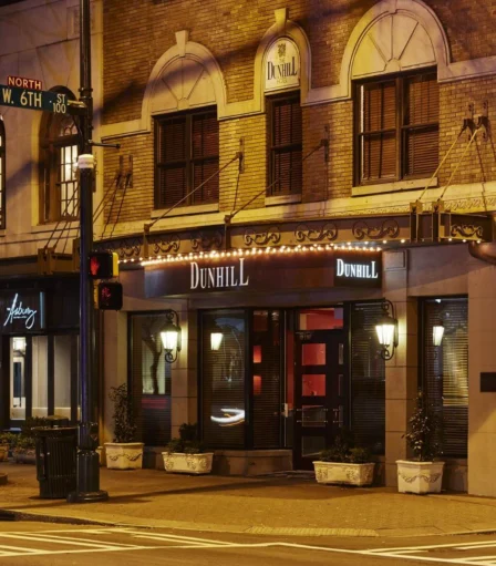 Warmly lit facade of The Dunhill Hotel on a quiet Charlotte street at night.