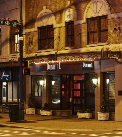 Warmly lit facade of The Dunhill Hotel on a quiet Charlotte street at night.