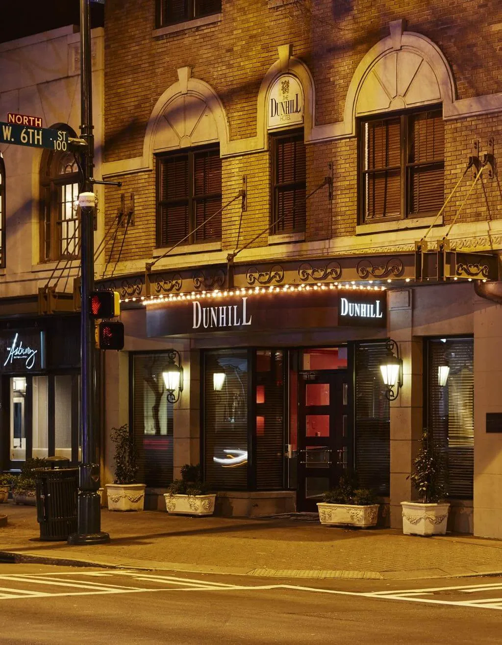 The exterior of the Dunhill Hotel at night, with its sign and lights visible.