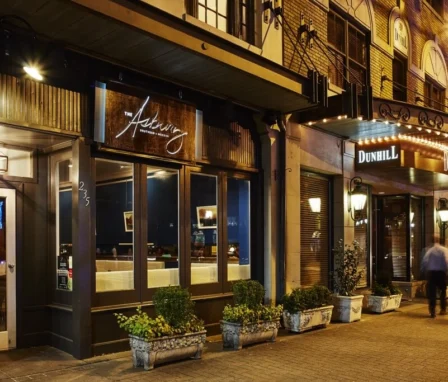 A couple walks near The Dunhill Hotel's warmly lit entrance in Charlotte, NC.