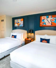Elegant twin beds in a cosy boutique hotel room with vibrant artwork.