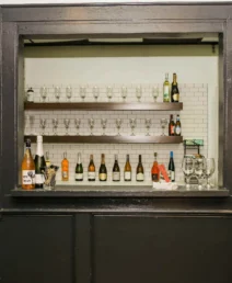 Cosy hotel bar with wine bottles, glasses, and warm ambiance in a boutique setting.
