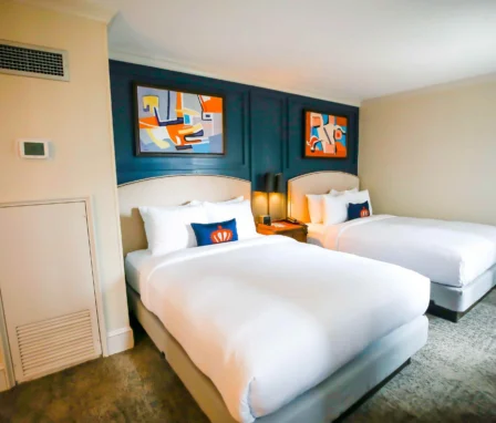 Elegant twin beds in a cosy room at The Dunhill Hotel, Charlotte, with contemporary artwork.