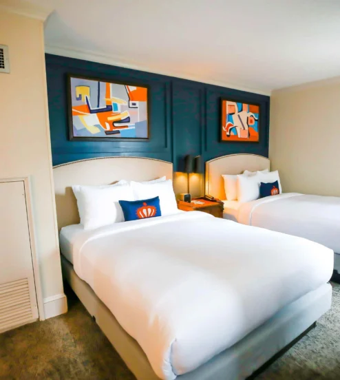 Elegant twin beds in a cosy room at The Dunhill Hotel, Charlotte, with contemporary artwork.