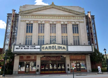 Historic theatre facade with family outside on sunny day.