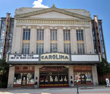 Historic theatre facade with family outside on sunny day.