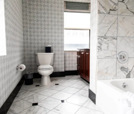 A bathroom with a toilet, bathtub, and marble tiles