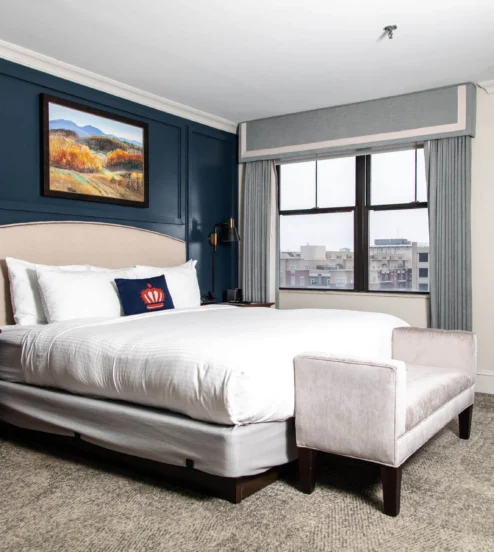 Elegant hotel room with a plush bed and city view, perfect for a relaxing stay.
