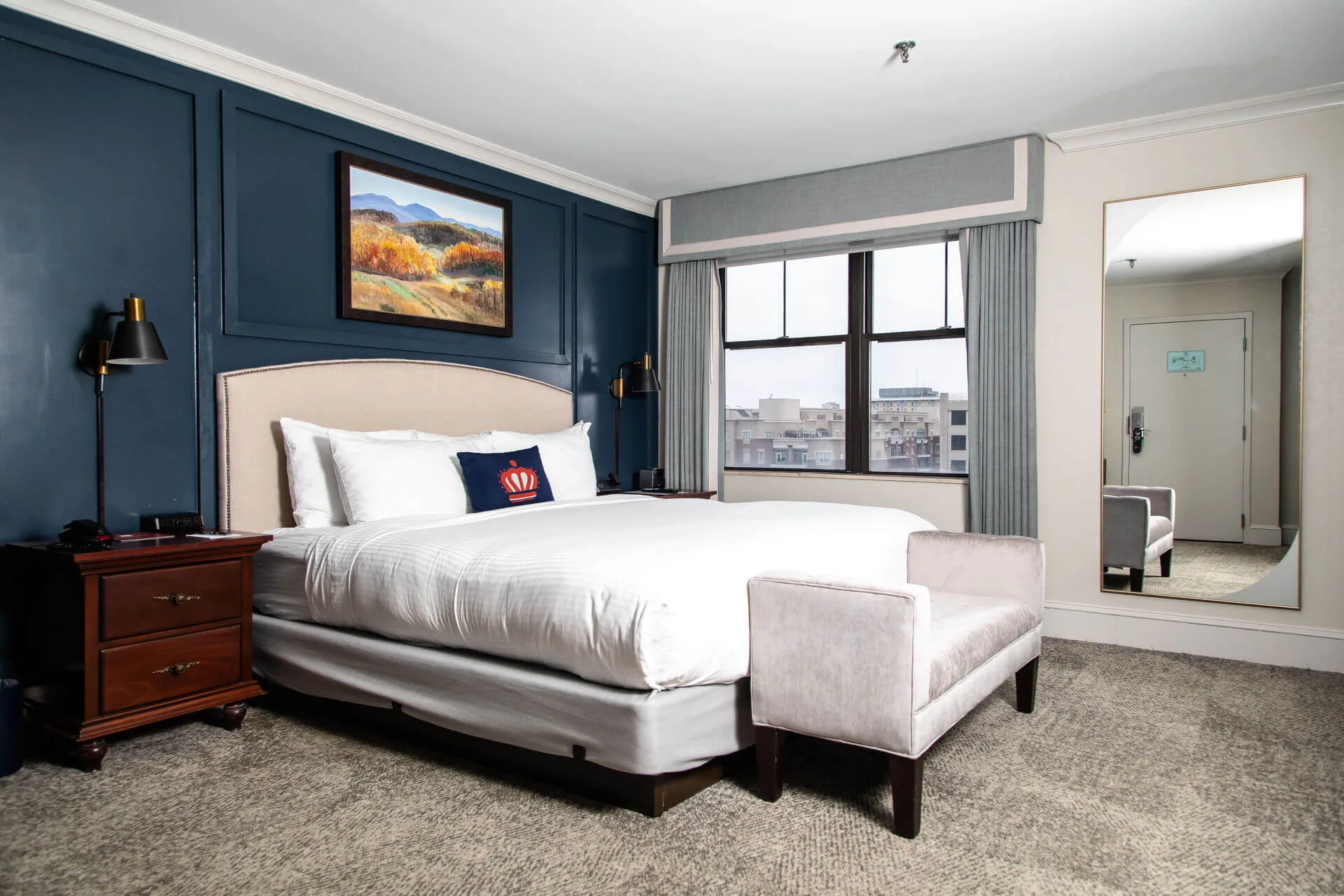 A hotel room with a large bed, window, and city view.