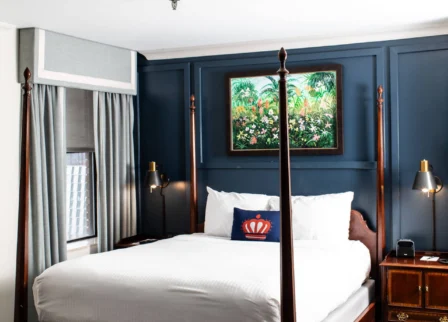 Elegant hotel room with a four-poster bed and a vibrant framed painting.