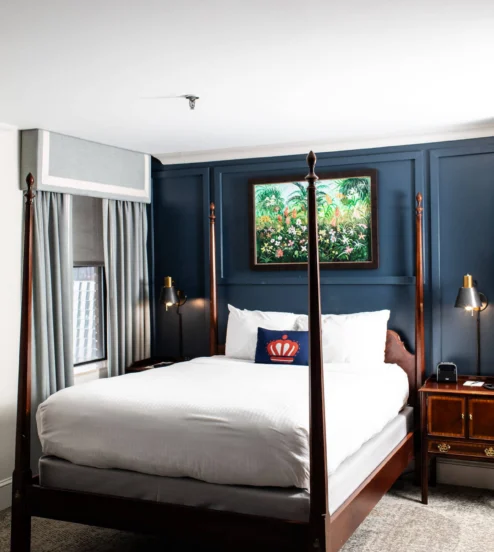 Elegant hotel room with a four-poster bed and a vibrant framed painting.